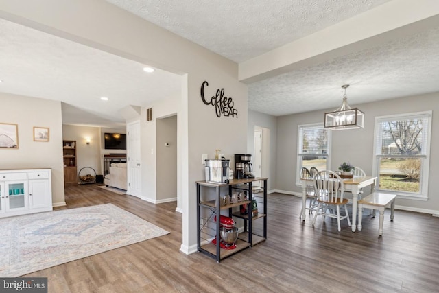 dining space featuring visible vents, baseboards, an inviting chandelier, wood finished floors, and a textured ceiling