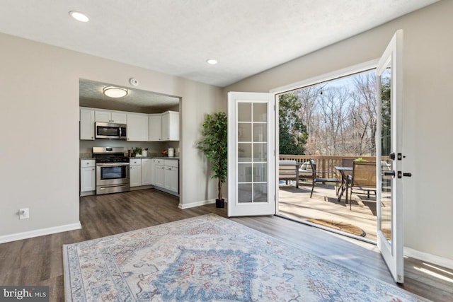 kitchen featuring baseboards, dark wood finished floors, stainless steel appliances, white cabinets, and french doors