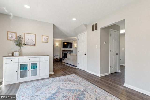 corridor featuring dark wood finished floors, visible vents, recessed lighting, and baseboards