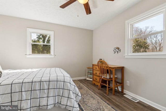 bedroom with a textured ceiling, wood finished floors, visible vents, and baseboards