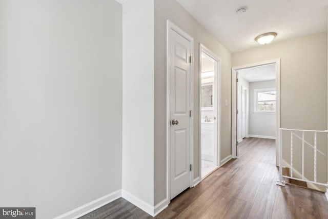 hallway featuring dark wood finished floors and baseboards