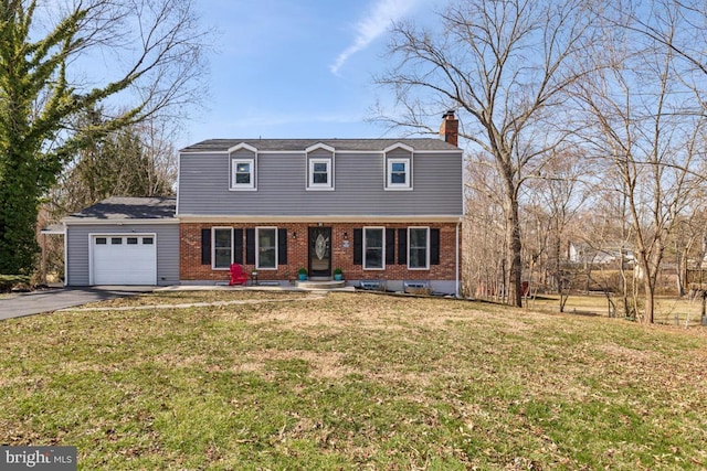 colonial house with a gambrel roof, a front lawn, aphalt driveway, a garage, and brick siding