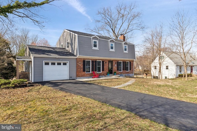 colonial home featuring a gambrel roof, driveway, an attached garage, brick siding, and a chimney