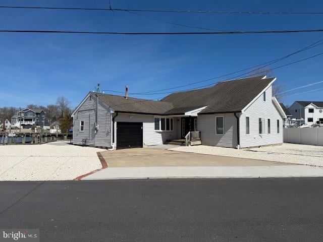 view of front of home with concrete driveway, an attached garage, and fence