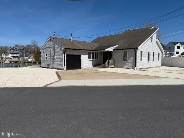 view of front of house with concrete driveway, a garage, and fence