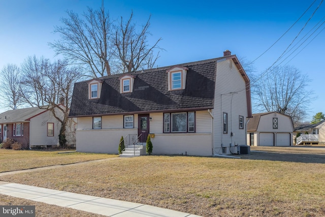 view of front of home with an outbuilding, a gambrel roof, a front lawn, and roof with shingles