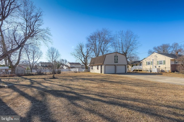 view of yard with an outbuilding, fence, a residential view, and driveway