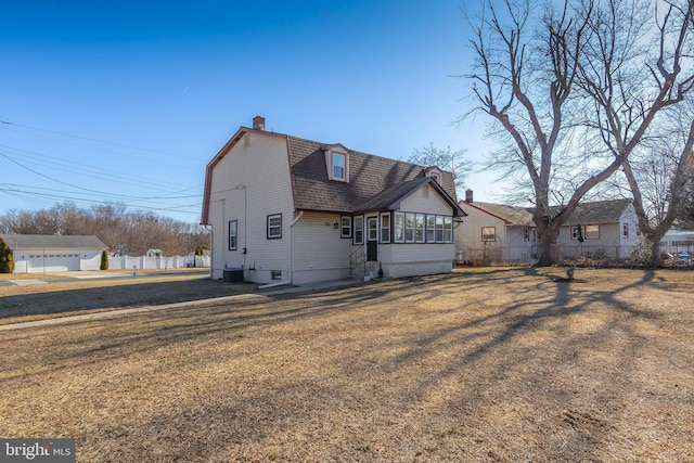 view of front of home featuring a gambrel roof, central AC, fence, a sunroom, and a chimney