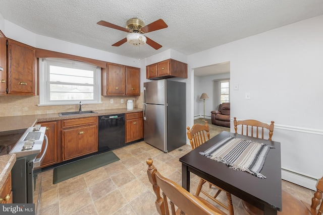 kitchen with a wealth of natural light, a baseboard radiator, appliances with stainless steel finishes, and a sink