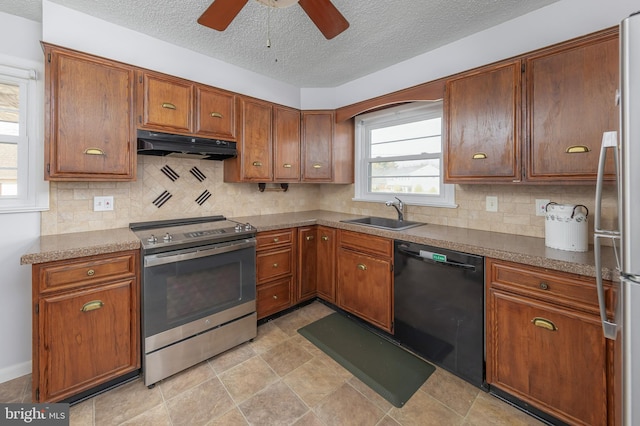 kitchen featuring under cabinet range hood, a sink, backsplash, appliances with stainless steel finishes, and brown cabinetry