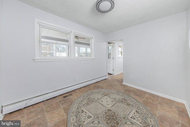 spare room featuring visible vents, baseboards, baseboard heating, and a textured ceiling