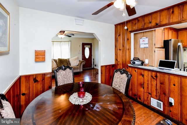 dining area with wood walls, ceiling fan, visible vents, and a wainscoted wall