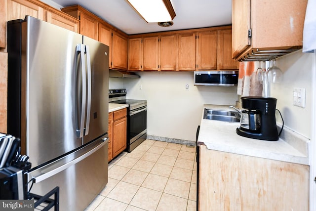 kitchen featuring a sink, light tile patterned floors, light countertops, and appliances with stainless steel finishes