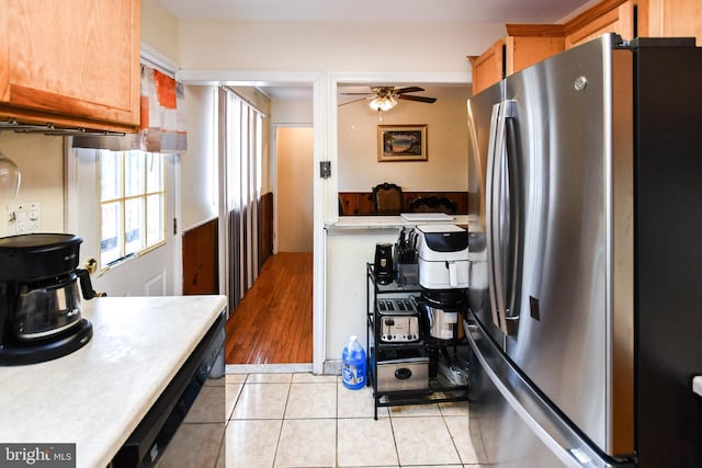 kitchen with black dishwasher, light countertops, freestanding refrigerator, a ceiling fan, and light tile patterned flooring