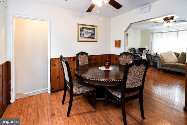 dining room featuring arched walkways, light wood-style floors, and ceiling fan