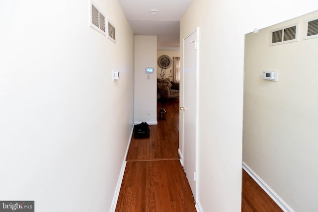 hallway with visible vents, baseboards, and wood finished floors