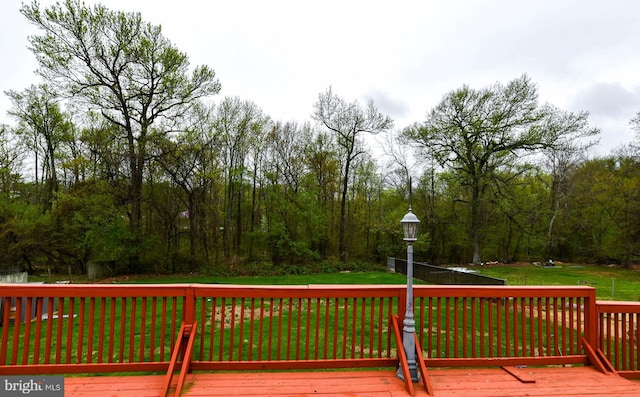 wooden terrace with a forest view and a lawn