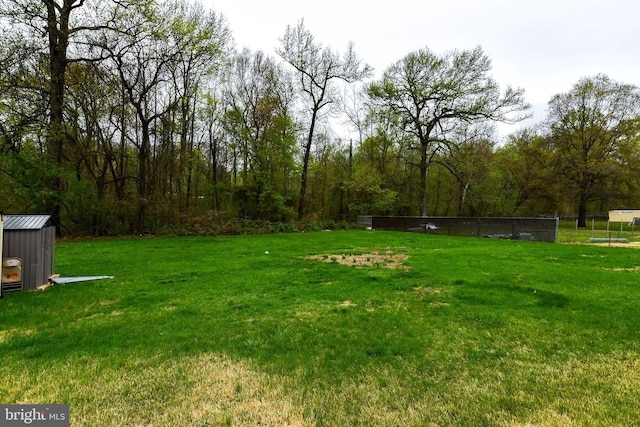 view of yard featuring an outbuilding, a shed, and fence