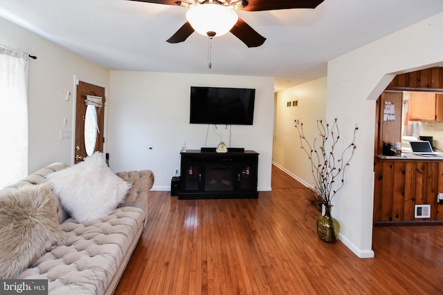 living area featuring visible vents, baseboards, arched walkways, a ceiling fan, and hardwood / wood-style floors