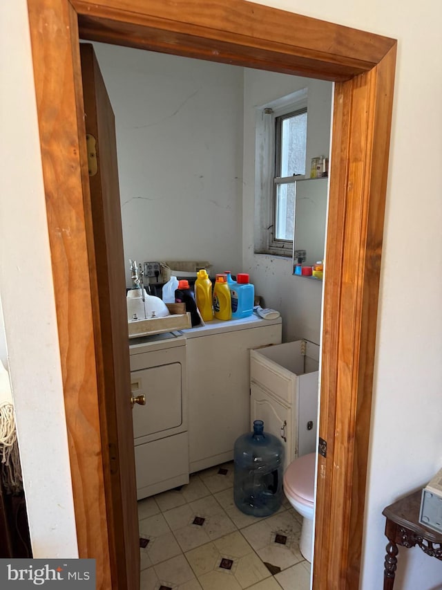 washroom with separate washer and dryer, light tile patterned flooring, and laundry area