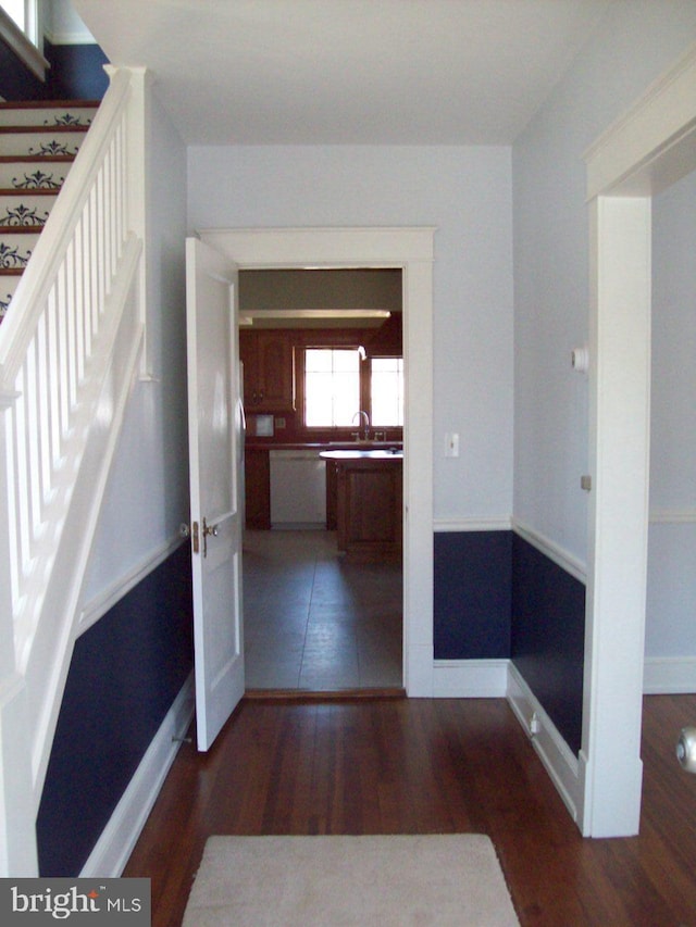 hallway with a sink, baseboards, wood finished floors, and stairs