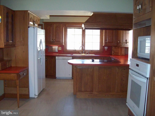 kitchen featuring brown cabinets, a peninsula, custom exhaust hood, white appliances, and a sink