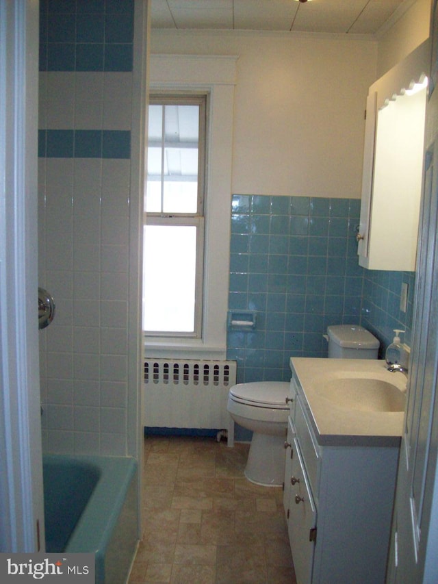 bathroom featuring toilet, vanity, tile walls, and radiator heating unit