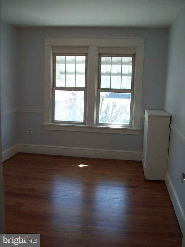 spare room featuring baseboards and wood finished floors