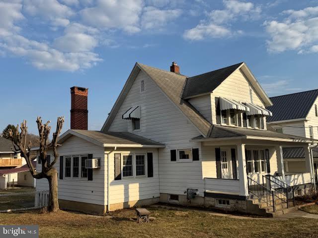 back of property with covered porch and a chimney