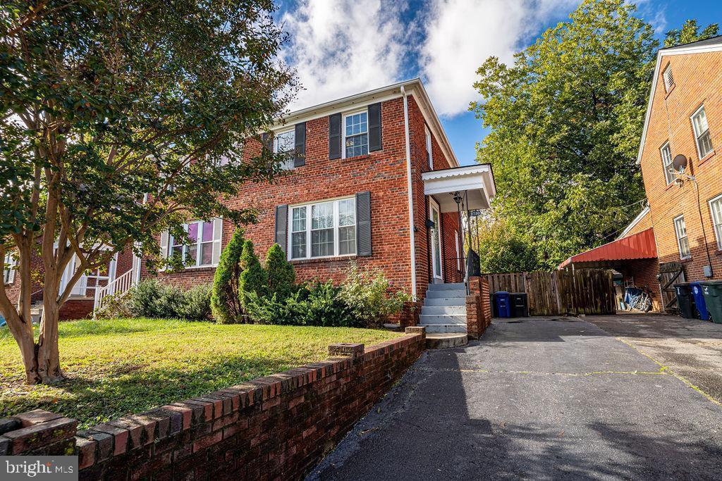 view of front of property with a front yard, fence, brick siding, and driveway