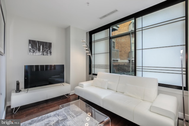 living room with visible vents, a wall of windows, baseboards, and wood finished floors