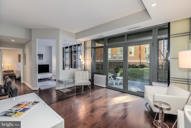 living room featuring visible vents, baseboards, wood finished floors, and floor to ceiling windows