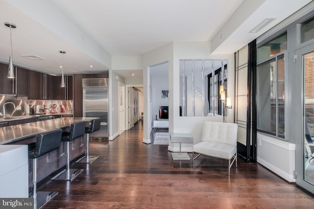 kitchen featuring dark wood-type flooring, dark brown cabinetry, stainless steel built in fridge, stainless steel counters, and modern cabinets