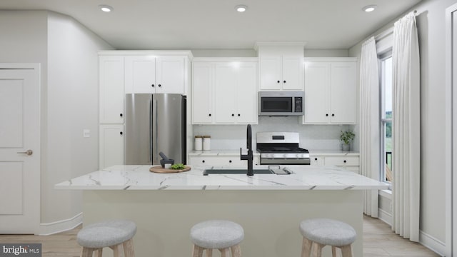 kitchen featuring white cabinets, stainless steel appliances, and a kitchen bar