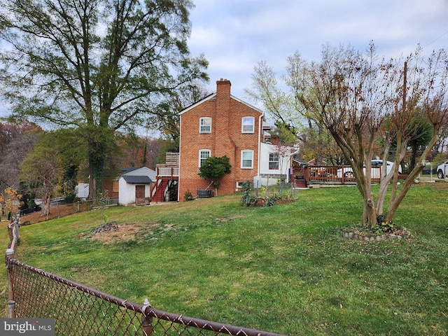 view of side of home featuring brick siding, fence, a lawn, a chimney, and an outdoor structure