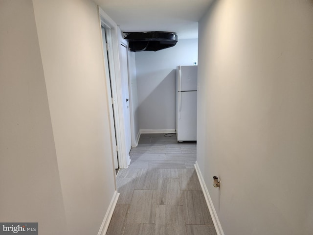 corridor with light wood-style floors and baseboards