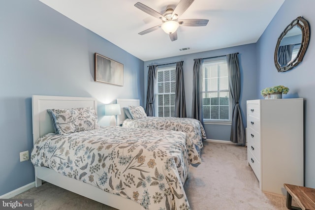 bedroom featuring ceiling fan, light colored carpet, visible vents, and baseboards