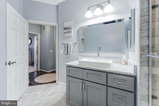 bathroom with visible vents, marble finish floor, tiled shower, baseboards, and vanity