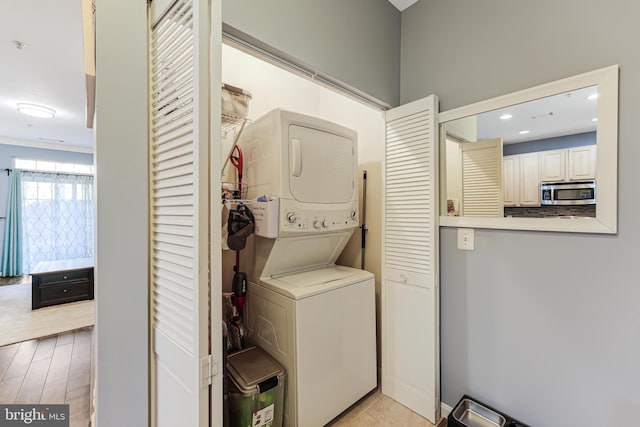 laundry room featuring laundry area, light wood-type flooring, and stacked washing maching and dryer