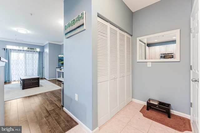 corridor featuring ornamental molding, baseboards, and wood finished floors