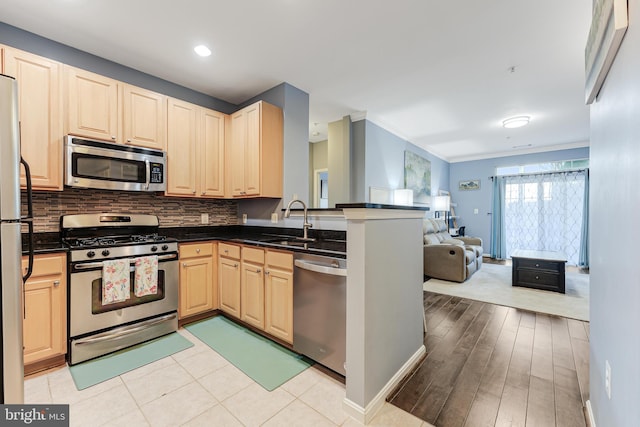 kitchen featuring a sink, dark countertops, light brown cabinets, and stainless steel appliances