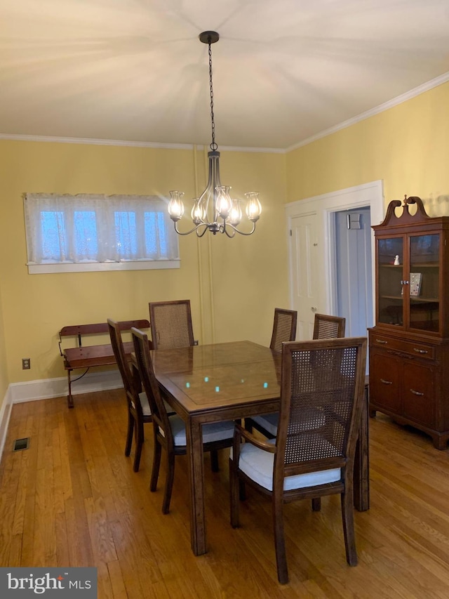 dining area featuring visible vents, a notable chandelier, light wood-style flooring, crown molding, and baseboards