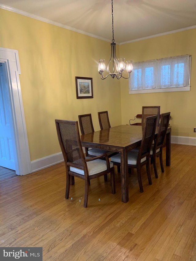 dining room with a notable chandelier, baseboards, crown molding, and light wood-style floors