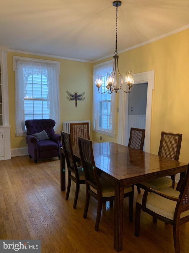 dining space featuring a notable chandelier, light wood-type flooring, crown molding, and baseboards