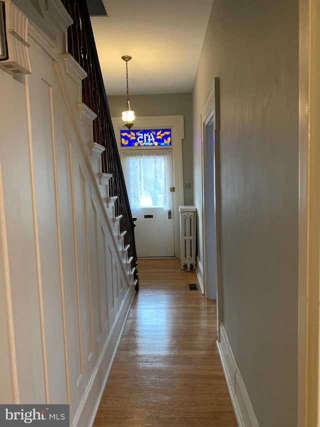 hall with visible vents, wood finished floors, and stairs