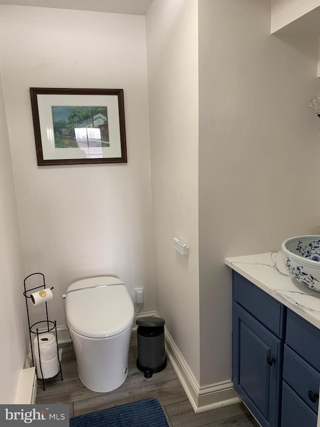 half bathroom with baseboards, wood finished floors, and vanity