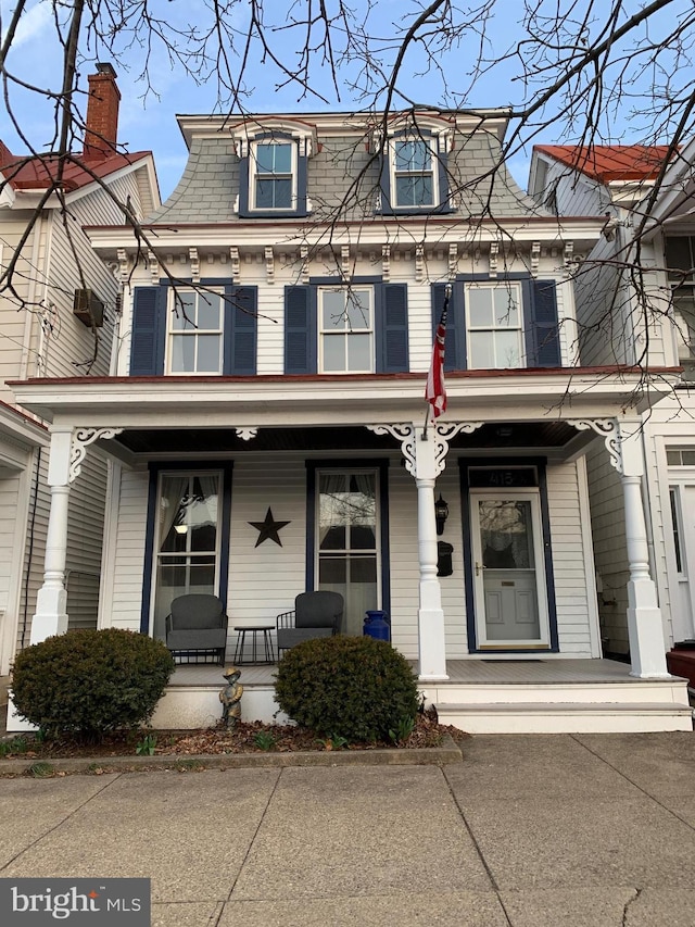 second empire-style home featuring mansard roof and covered porch