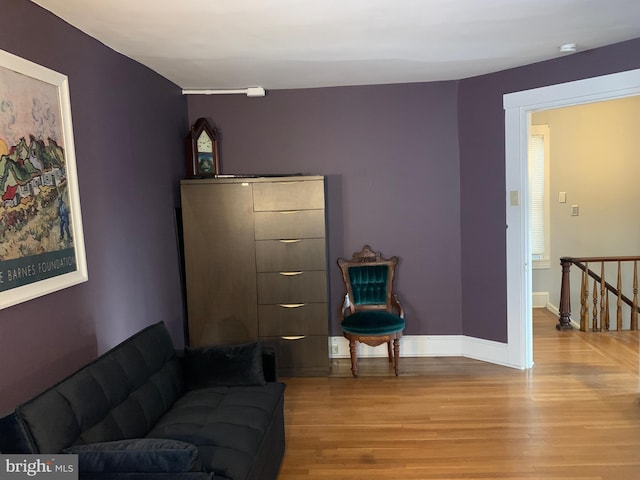 living area with light wood-style flooring, an upstairs landing, and baseboards