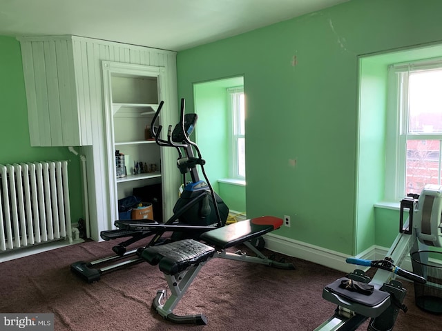 exercise area with radiator, baseboards, and carpet floors