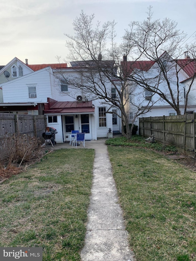 back of house featuring a yard, a patio, and a fenced backyard